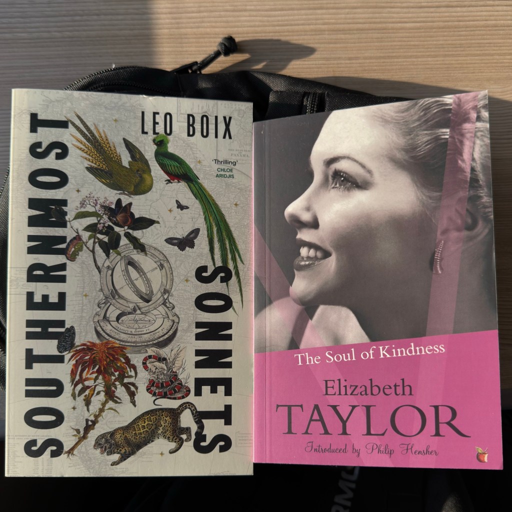 Two books rest side by side on a train table with a wooden-effect finish. On the left, Southernmost Sonnets by Leo Boix shows a vivid collage of birds, butterflies, flowers, a snake, and a leopard layered over a map, with a quote from Chloe Aridjis. On the right, The Soul of Kindness by Elizabeth Taylor features a black-and-white photo of a smiling woman, softened by a pink title band. A black bag peeks out beneath them.